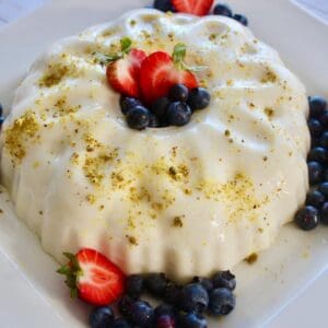 ashtello topped with some berries, ground pistachios, and a drizzle of simple syrup