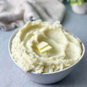 a close up shot of creamy mashed potatoes bowl with pieces of butter