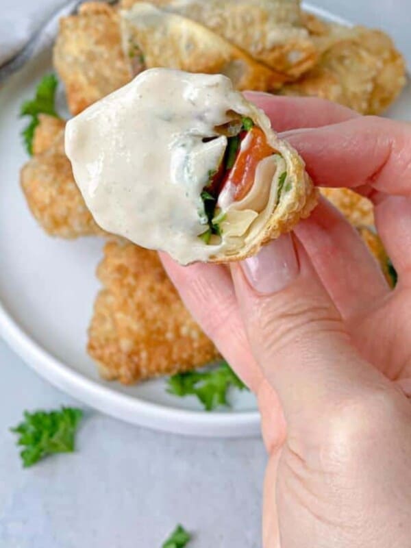 A bite of egg rolls stuffed with shawarma and veggies and dipped in tahini.