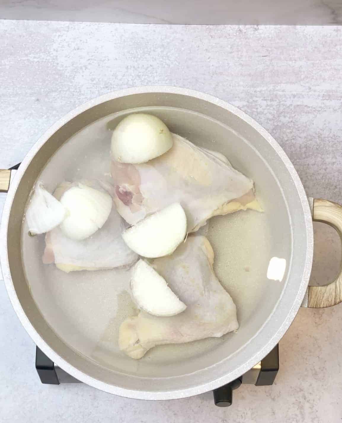 the first step to prepare mloukhieh is to boil the whole chicken or chicken breast in a deep pot with halved onion