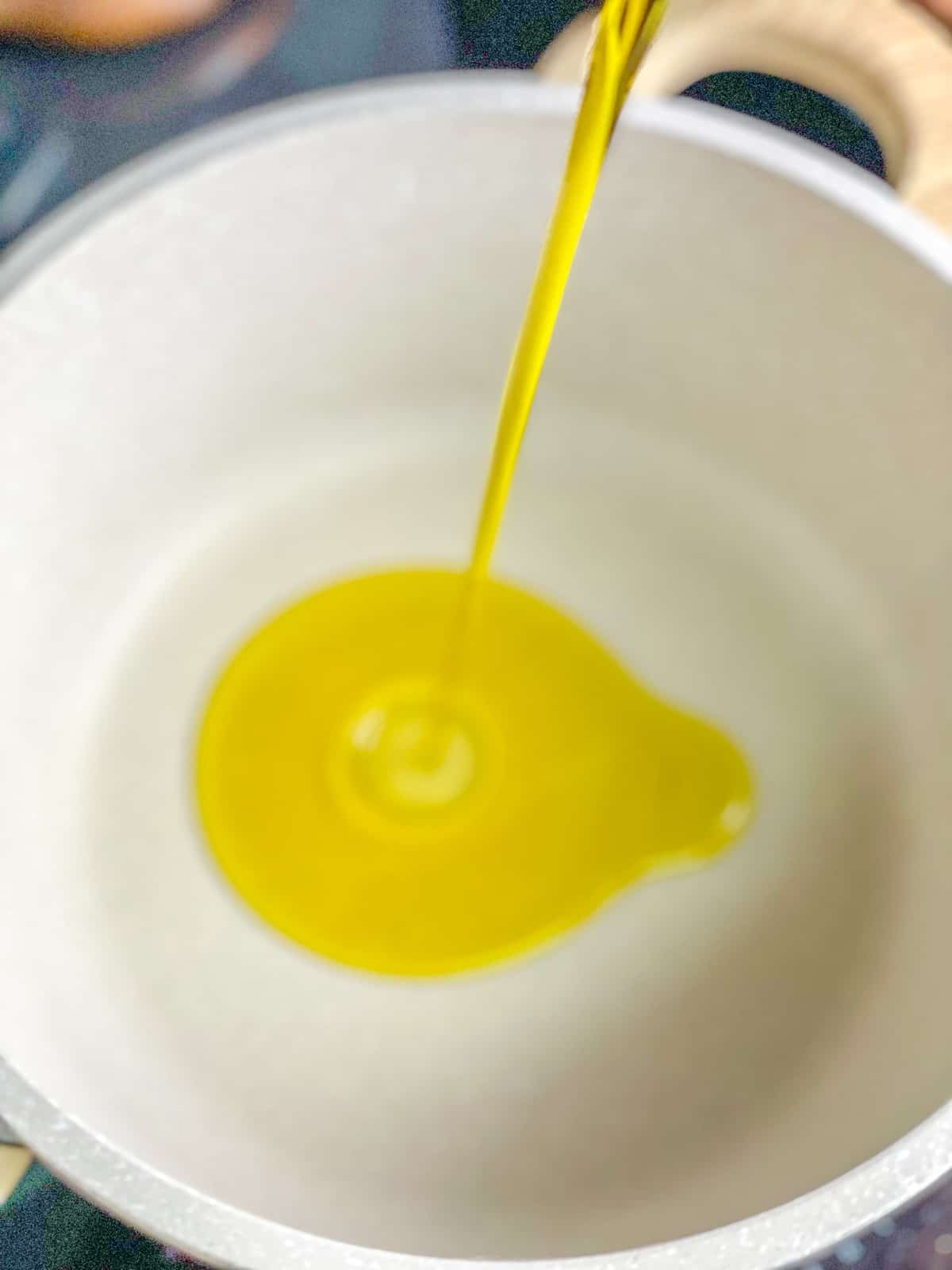adding olive oil in a medium pot
