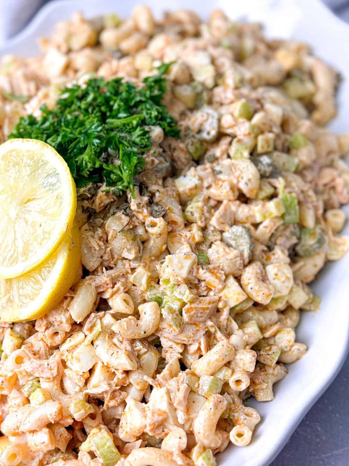 Tuna Egg Salad Recipe A bowl of tuna egg salad, featuring a creamy mixture of flaked tuna, chopped hard-boiled eggs, mayonnaise, and finely diced vegetables such as celery and onion, garnished with a sprinkle of paprika. The salad is served on a white plate with a fork on the side.