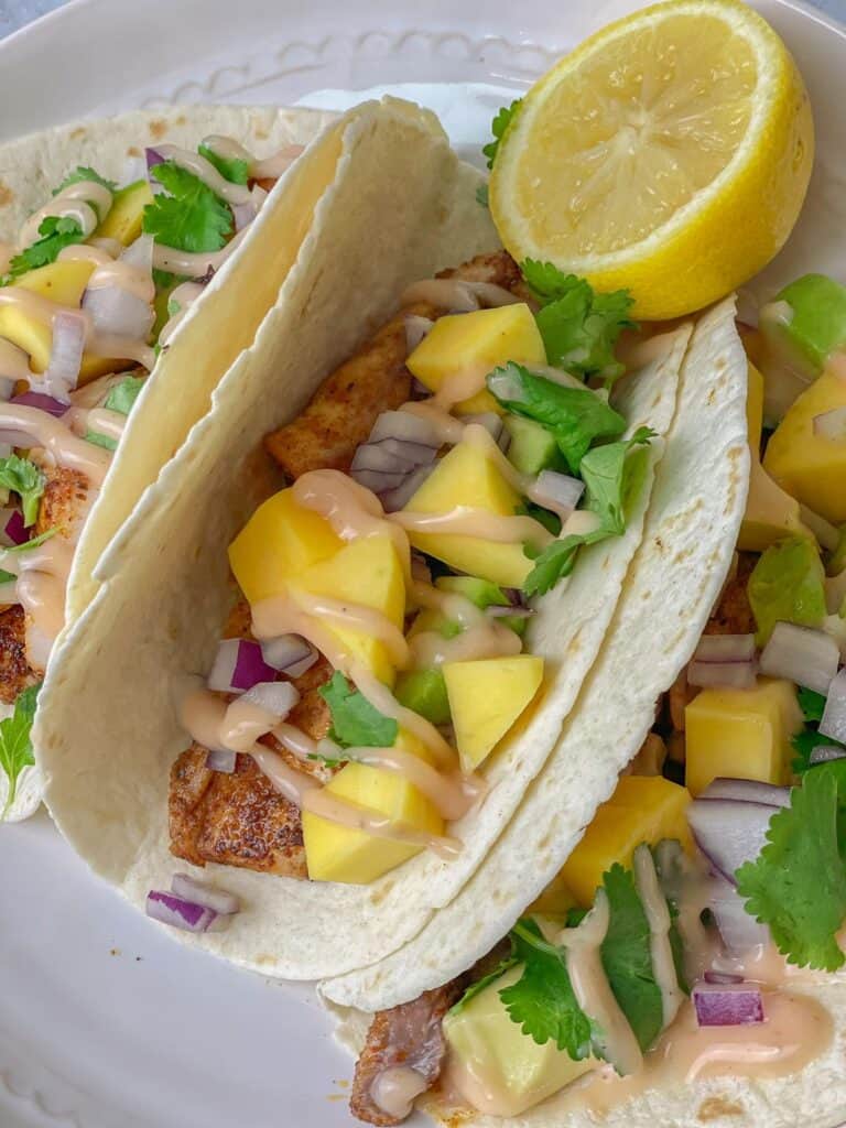 Delicious blackened mahi mahi fish turned into flavor-packed tortilla tacos that are easy and packed with mangoes, avocado, cilantro, and a mahi sauce