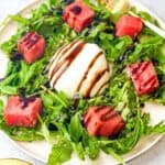 Elegant summer salad with burrata cheese, watermelon, arugula, and balsamic drizzle