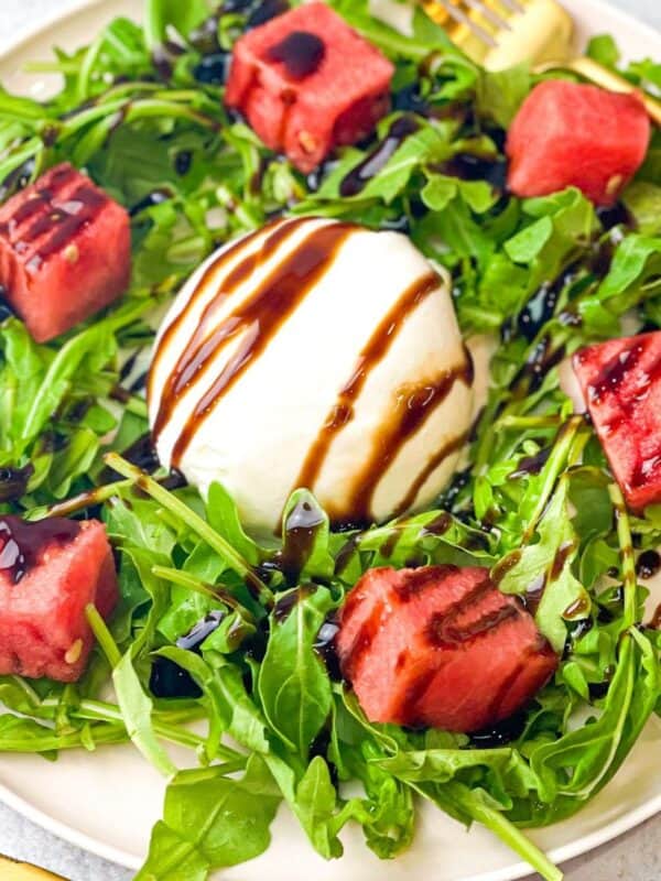 Elegant summer salad with burrata cheese, watermelon, arugula, and balsamic drizzle