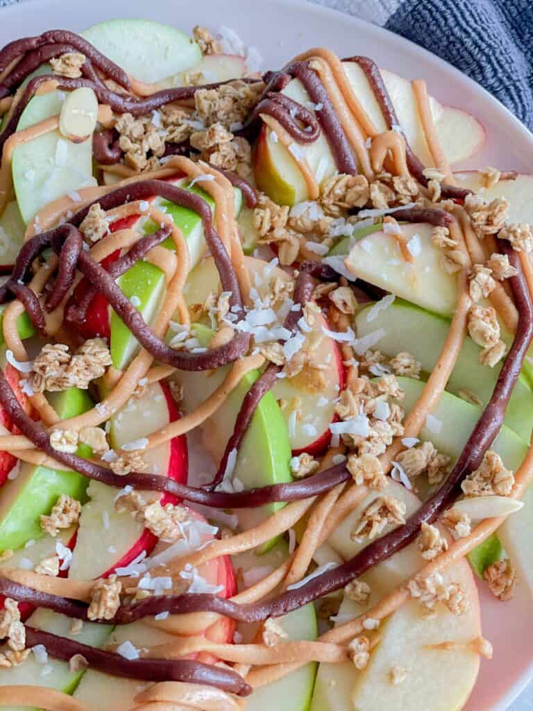 This snack comes together in less than 5 minutes to please all your senses. Sliced apples drizzled peanut butter, chocolate, and sprinkled with granola