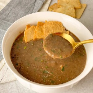 velvety brown lentils soup garnished with freshly chopped parsley and served with pita bread croutons