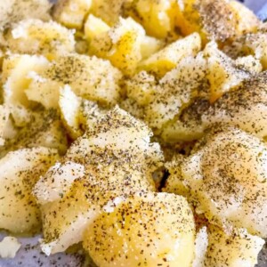 A plate packed with boiled potatoes and garnished with delicious herbs.