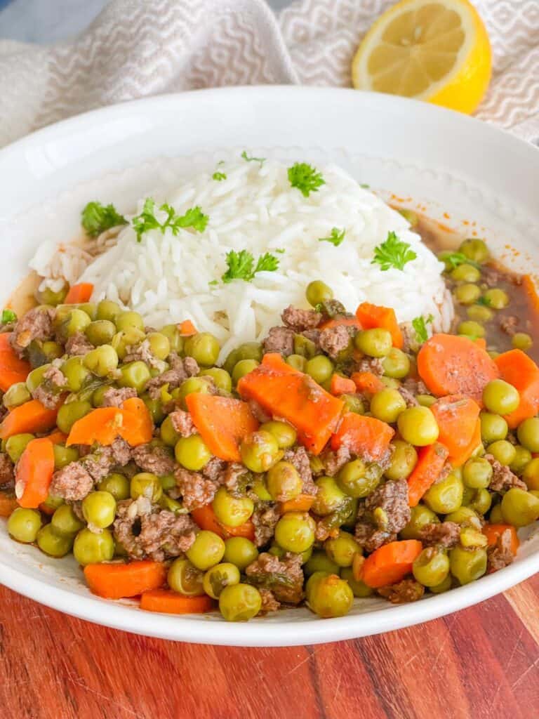 Tender green peas, orange carrots and juicy ground meat are simmered in tomato broth and served with white rice. Green parsley chops are sprinkled on the top of rice.