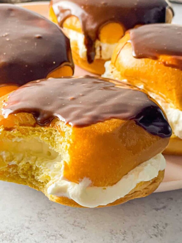 Fluffy brioche buns filled with cream and topped with melted chocolate.