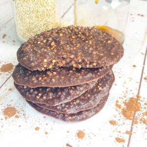 A stack of chocolate quinoa cookies next to a jar of tasty honey and quinoa