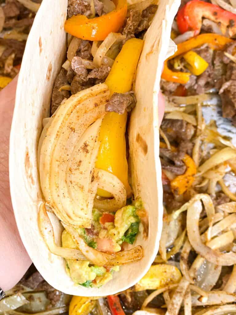 A warm tortilla filled with onions, colored peppers and flank steak is simply the best fajitas you will ever have!