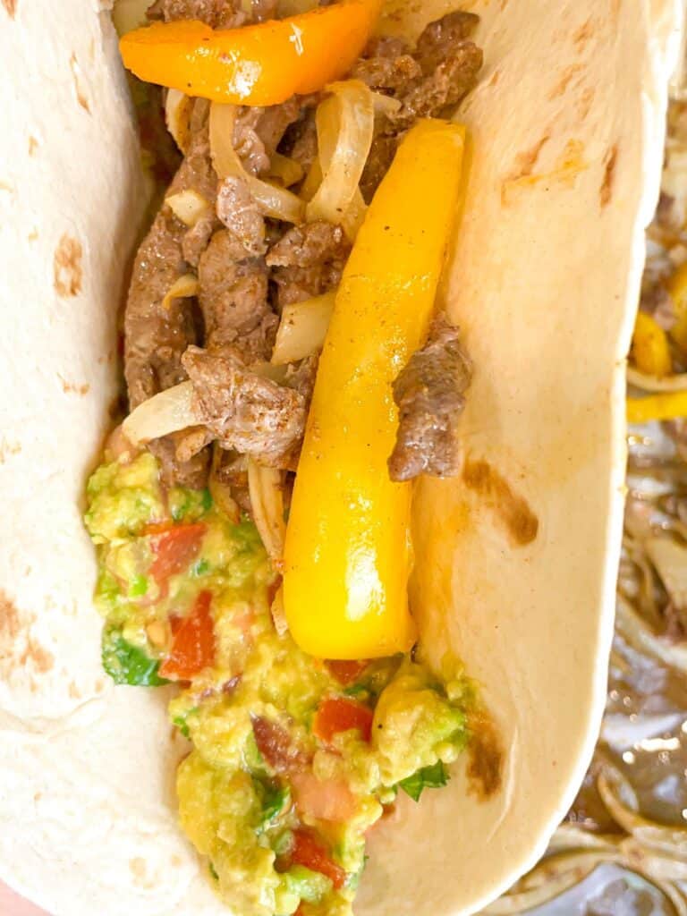 In a warm tortilla bread, fill the fajitas and guacamole to add more tasty flavors to your meal.