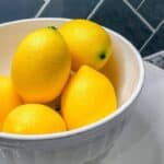 5 lemons stored on the counter in a glass bowl