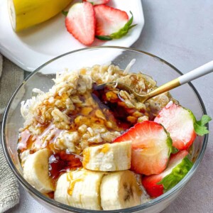 pudding oatmeal in a bowl topped with banana and strawberry slices and a drizz;e of honey