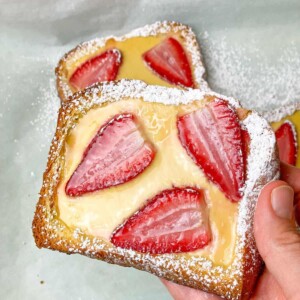 A hot slice of custard brioche toast garnished with strawberries ready to be served