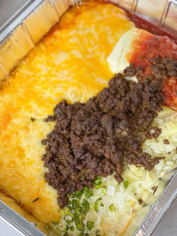 Taco Queso Dip is a mix of well seasoned ground beef, spices, and layers upon layers of cheese.