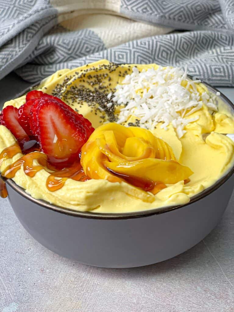 Delicious bowl of mango ice cream with your favorite fruits and a drizzle of honey
