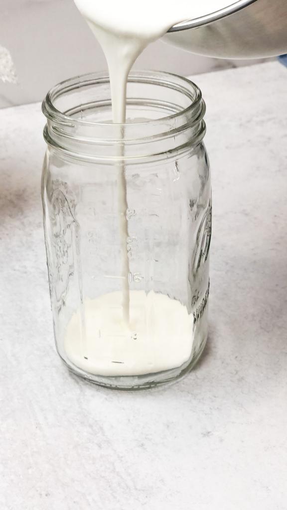 Pour milk and kefir grains in a sterile glass jar to make kefir yogurt.