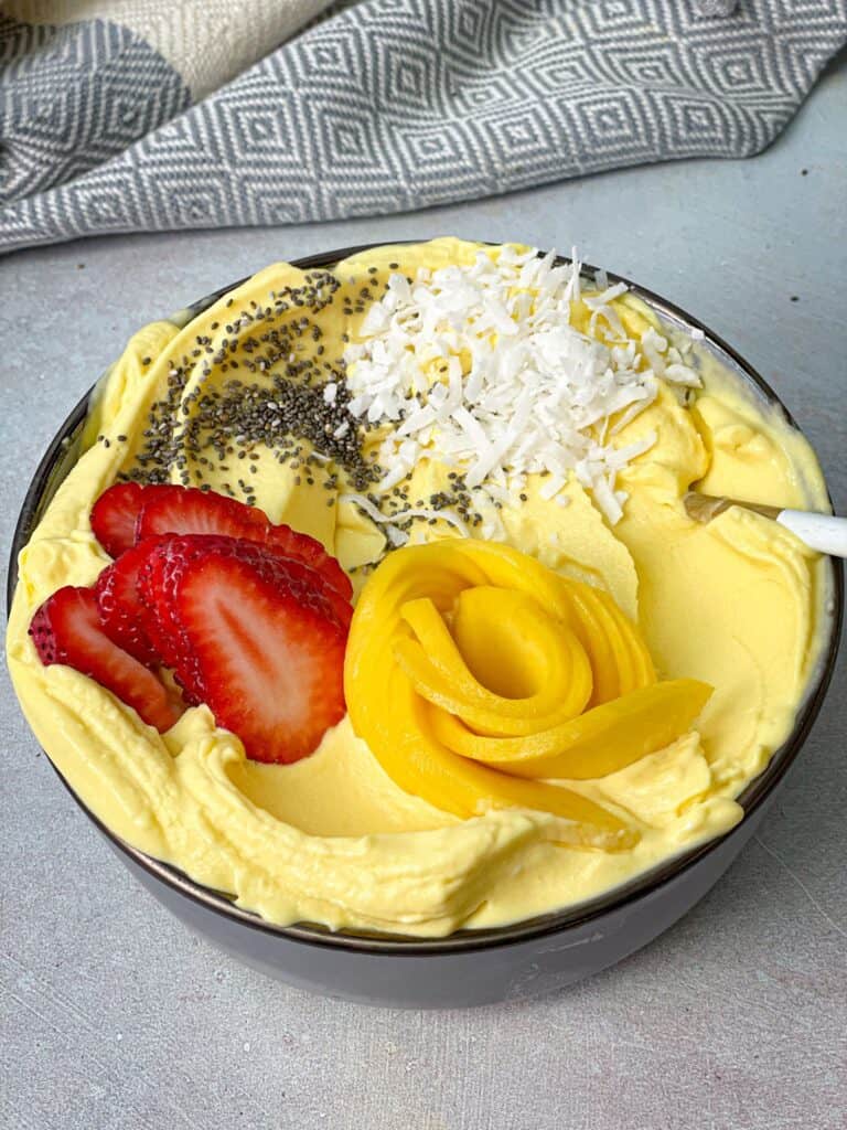 Add strawberry, coconut flakes, and Chia seeds to your bowl of mango ice cream to get the best treat ever.
