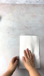 A hand covering a puff pastry dough with a kitchen paper towel.