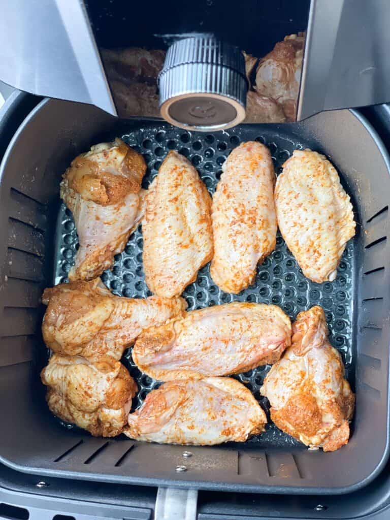 Well-seasoned chicken wings are placed in the air fryer and flipped mid way.