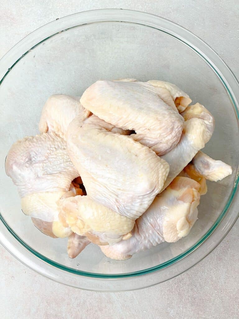 Whole chicken wings washed and dried sitting in the bowl waiting to be cut into drumettes, wingettes, and tips.