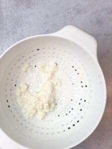 Kefir milk strained and kefir grains are collected to be used in making new batches of kefir.