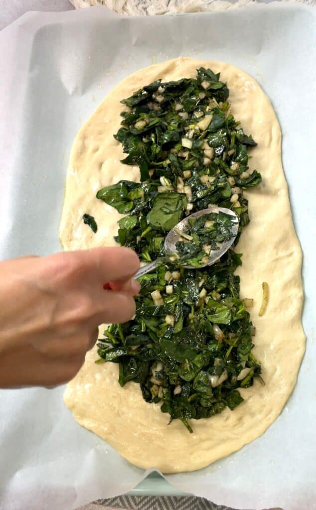 Spinach and onion mixture placed on the center of the rectangular shaped dough.