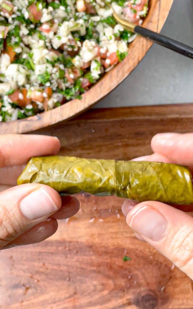 A grape leaf perfectly rolled over the stuffing and ready to be stacked in the pot
