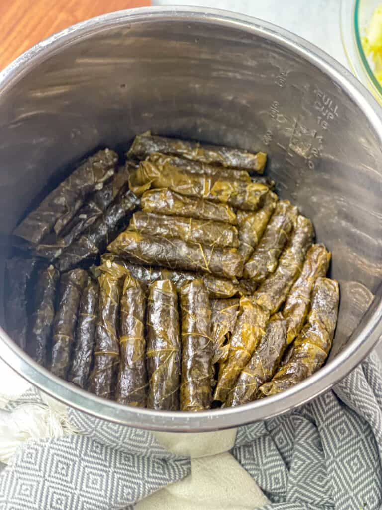 Instant pot filled with perfectly rolled grape leaves ready to be on fire