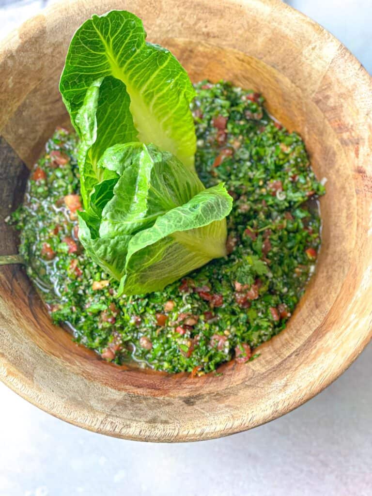 Zesty, tangy, and juicy easy Lebanese tabbouleh salad swimming in its own juices and served with green lettuce leaves.