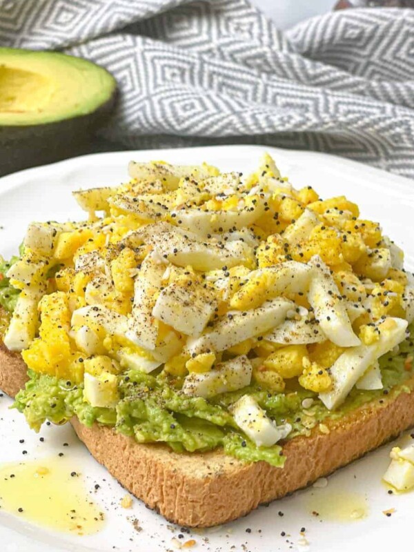 An exquisite twist on classic avocado toast, featuring creamy mashed avocado atop a slice of artisanal bread, garnished with perfectly boiled eggs, offering a nutritious and flavorful breakfast or snack option.