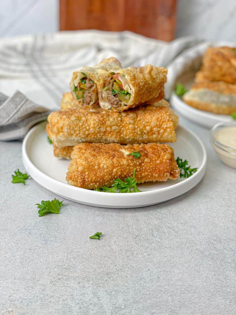 A plate of golden crispy egg rolls stuffed with beef shawarma ready to be served