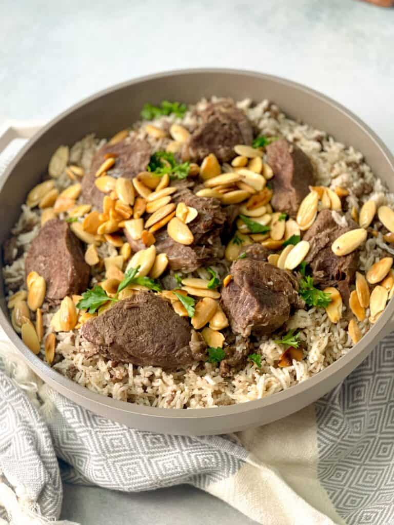 Fluffy rice with ground beef topped with beef shanks, roasted almonds, and parsley. This mansaf dish is the perfect comfort food.