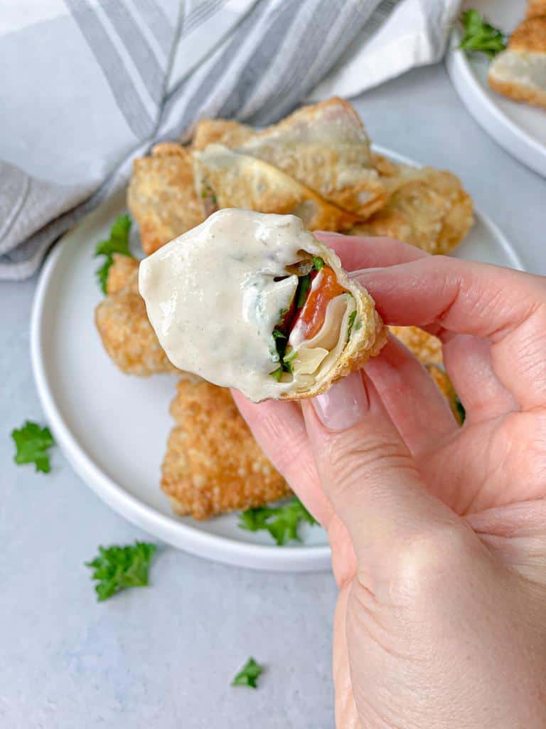 A bite of egg rolls stuffed with shawarma and veggies and dipped in tahini