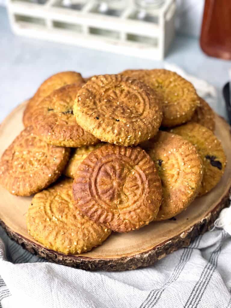 A dozen of Kaak El Eid on a wooden board. A delicious sweet bread seasoned with a delicious spice mix made up of anise, cloves, nutmeg, cinnamon, mahlab, sesame seeds, and a hint of caraway seed.