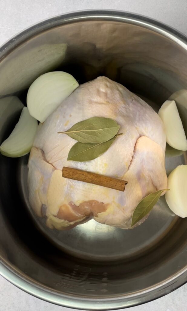 whole chicken in the instant pot with bay leaves, cinnamon stick, and cubed onion