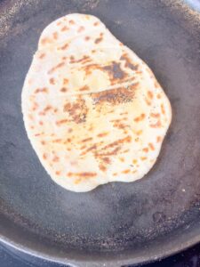 one gluten free flat bread placed on an iron skillet with a golden brown color and a slightly crisp texture