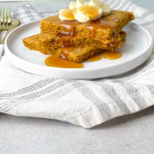 sheet pan pumpkin pancakes topped with chopped bananas and drizzled with honey