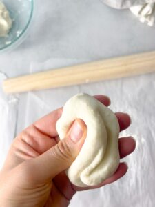 a woman squeezing the naan bread dough