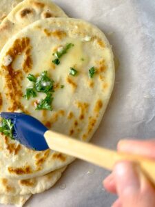 perfect gluten free naan bread garnished with butter, garlic, and parsley