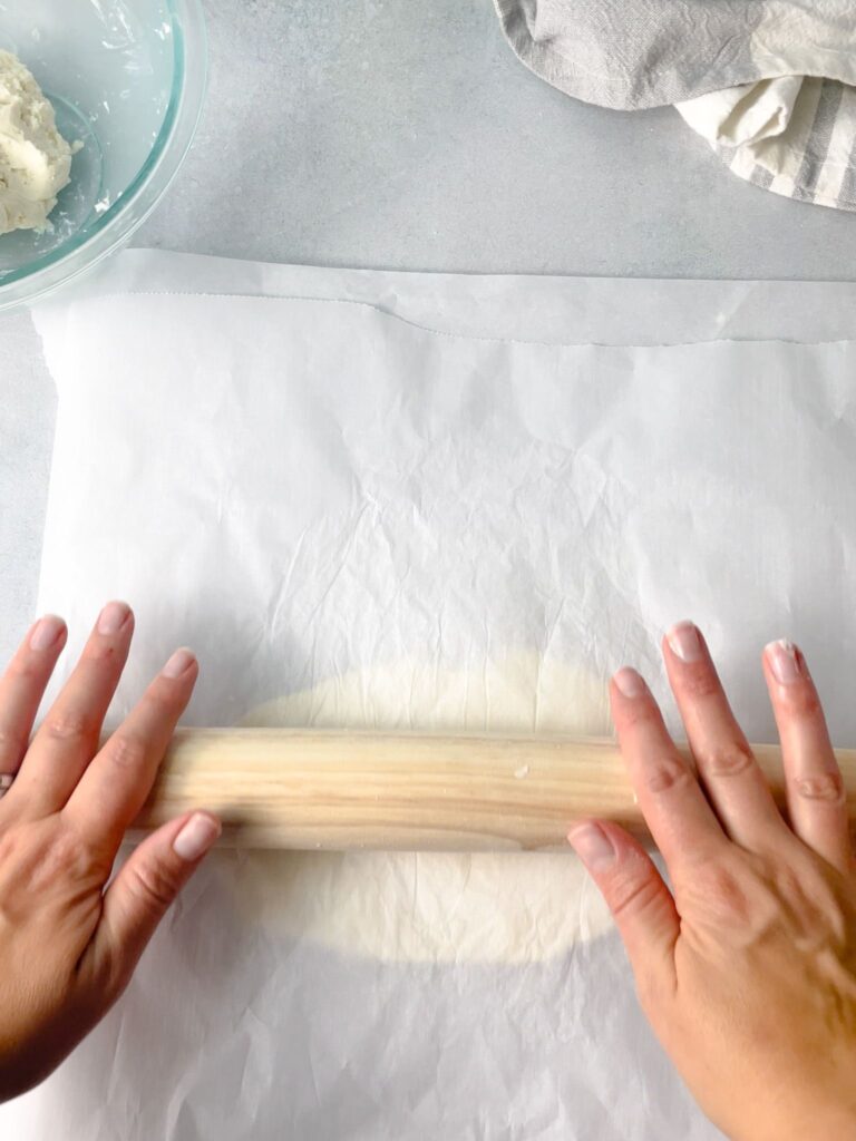 Naan bread dough rolled between two parchment papers