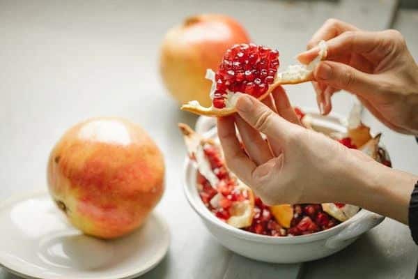 a woman trying to separate pomegranate seeds