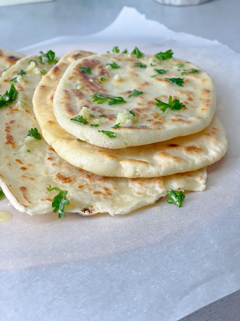 Buttery garlic naan breads garnished with cilantro are so soft and perfect for mopping up curries and stews.