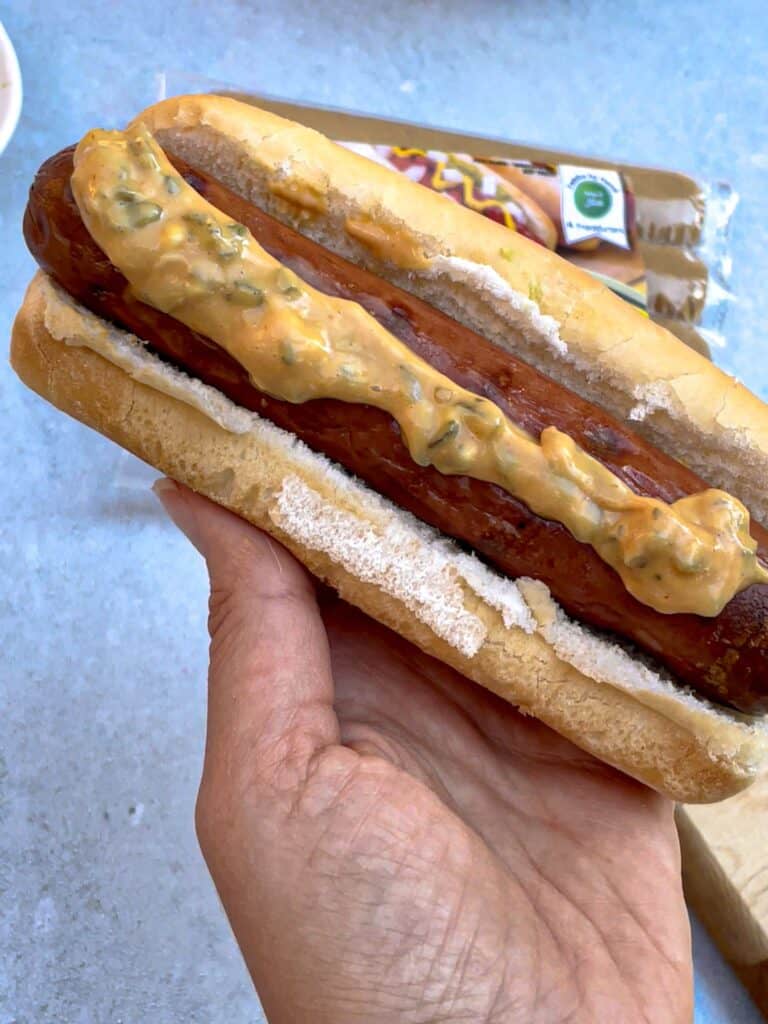 A hotdog in a sandwich topped with a mix of ketchup, mayo, mustard, and relish!