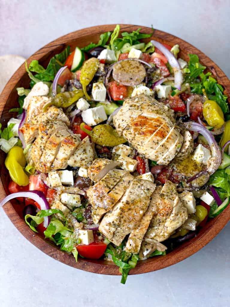 A bowl of Greek salad with slices of grilled chicken
