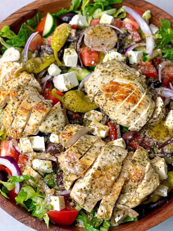 A bowl of Greek salad with slices of grilled chicken.
