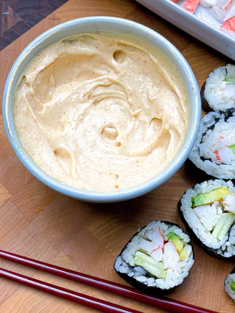 A smooth and creamy bowl of sushi sauce with some sushi rolls