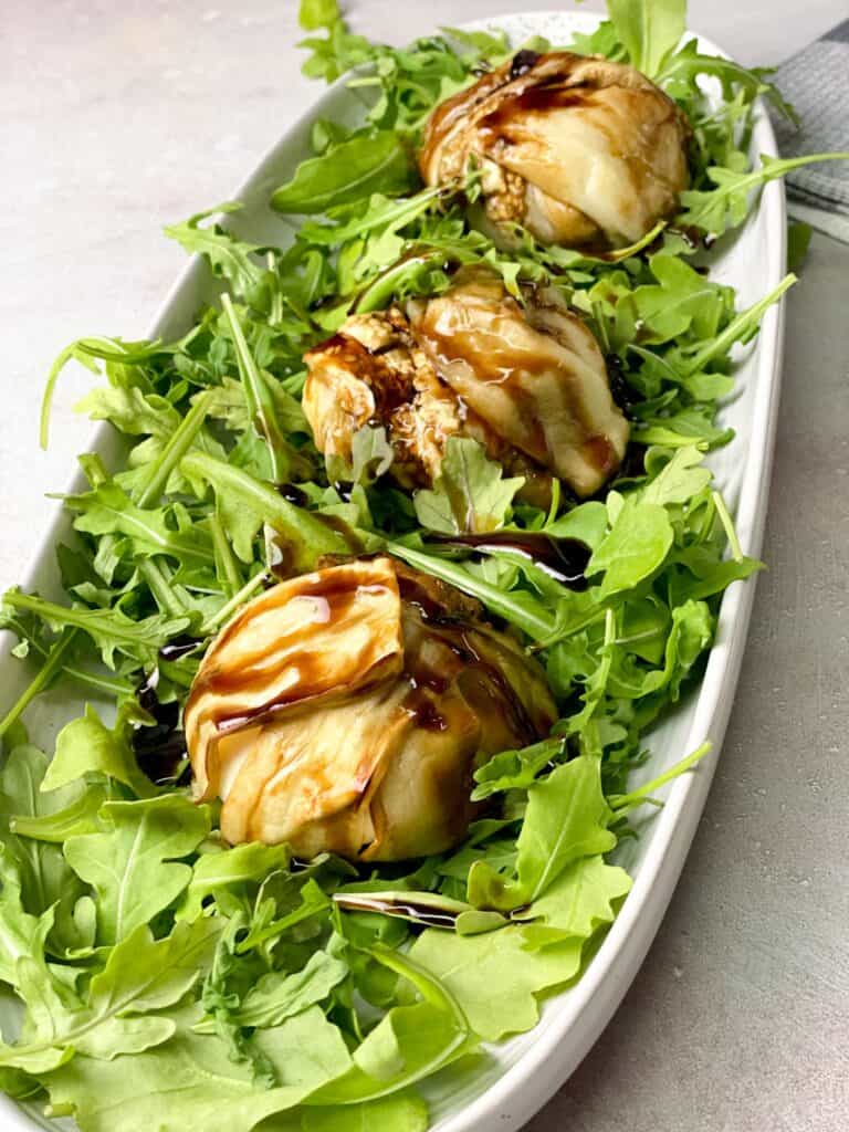 a beautiful platter of burrata wrapped with tender eggplants on the arugula layer and glazed with balsamic reduction